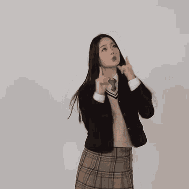 a girl in a school uniform is dancing and pointing up .