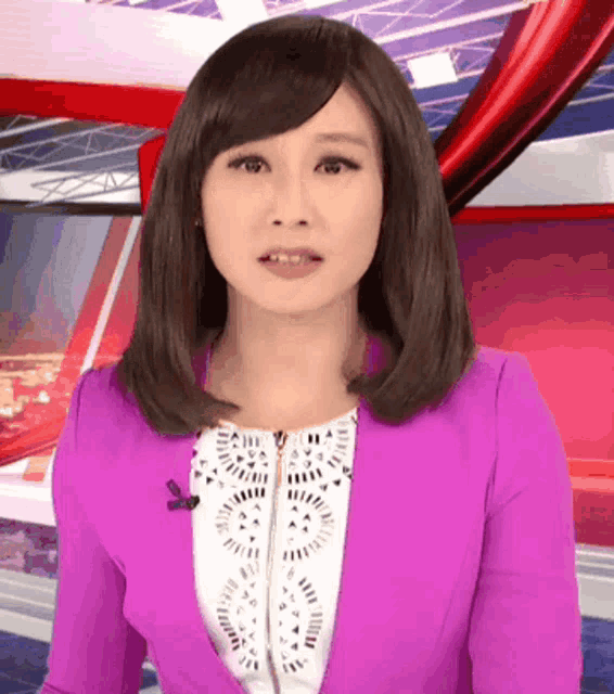 a woman in a purple jacket and white top stands in front of a red circle