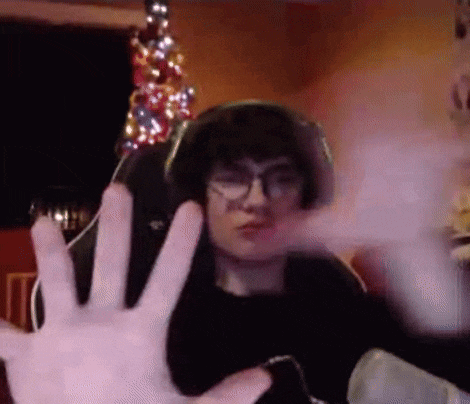 a man wearing glasses and headphones is sitting in front of a christmas tree and making a funny face .