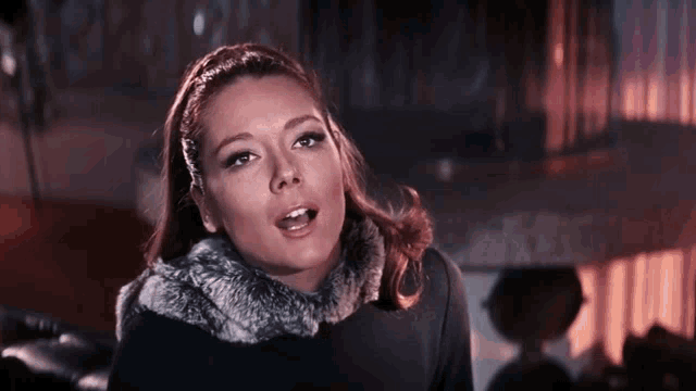 a woman with a fur collar on her neck is looking at the camera