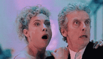 a man and a woman are standing next to each other with their mouths open and looking at something .