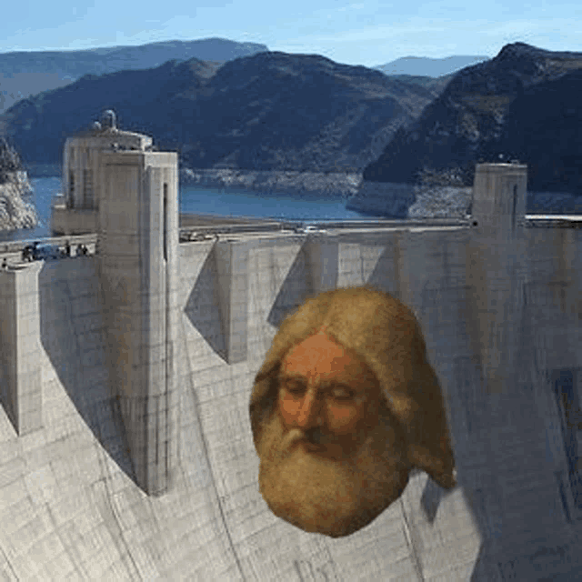 a statue of a man with a beard is flying over a dam with mountains in the background .