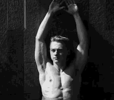 a black and white photo of a shirtless man with his arms up