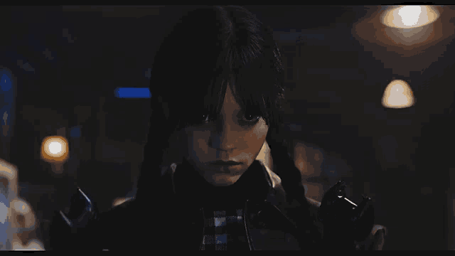 a girl with pigtails is holding a telephone in a dark room