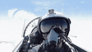a man wearing a helmet and goggles looks out the window of a plane