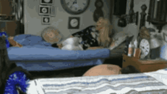 a woman is laying on a bed in a room with many clocks on the wall