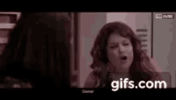 a woman is talking to another woman in a room while a gif is displayed on the screen .