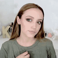 a woman with long brown hair is wearing a green sweater and earrings .