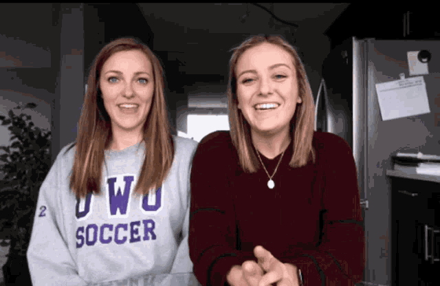 two women wearing sweatshirts that say soccer are smiling