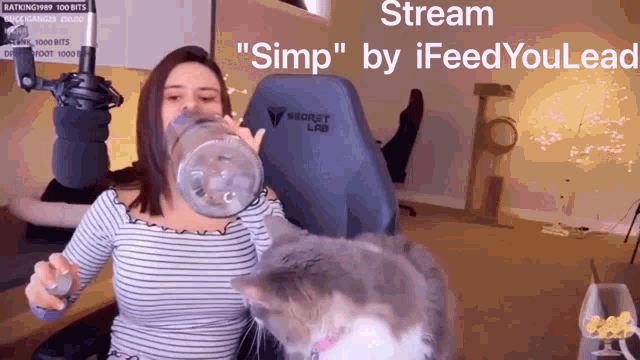 a woman is drinking from a bottle while sitting in a chair with a cat behind her