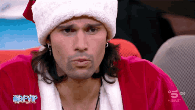 a man wearing a santa hat is on a television screen with the number 5 on it