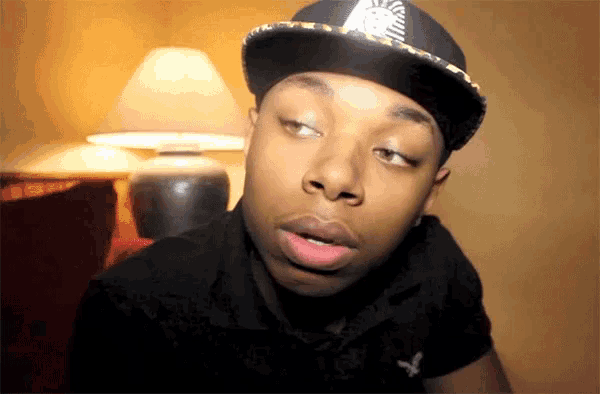 a young man wearing a hat with a pharaoh on it looks at the camera