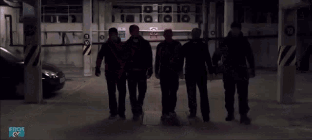 a man in a red shirt is standing in front of a group of men in black jackets .