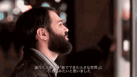 a man with a beard is looking up at the sky with chinese writing behind him