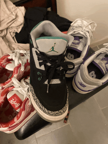 a pair of jordan shoes sits on a bench next to a pair of new balance sneakers