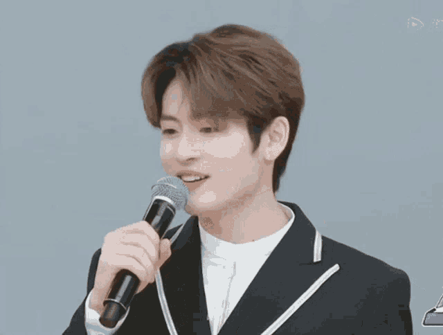 a man in a suit is holding a microphone and giving the peace sign