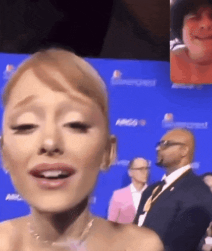 a close up of a woman 's face with a man in a suit behind her .