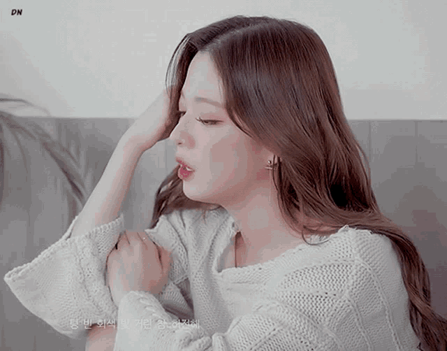 a woman wearing a white sweater with dn written on the bottom right