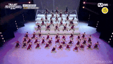 a group of people are dancing on a stage with a mnet logo in the corner