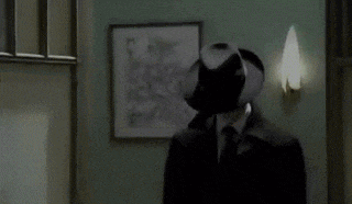 a man wearing a hat and a coat is standing in a hallway .