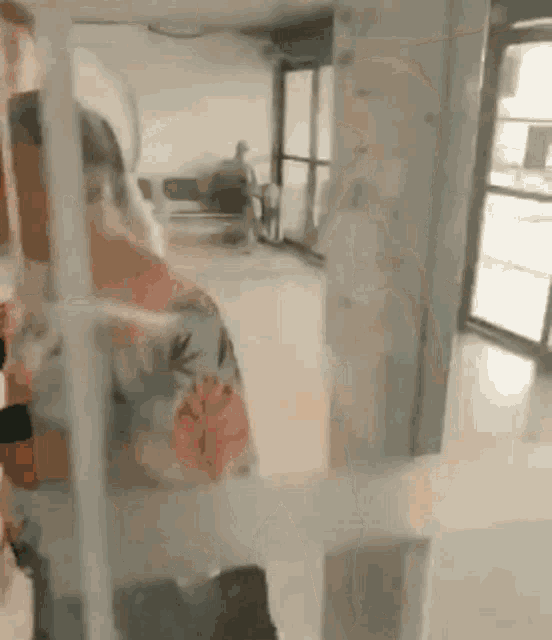 a woman in a floral shirt is standing in a room with a glass door .
