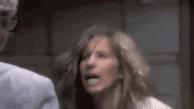 a woman with long hair is screaming at a man in a room .