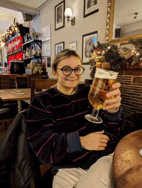 a woman in a striped sweater holds a glass of beer with a label on it that says ' king ' on it