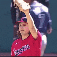 a baseball player wearing a red guardians jersey holds up his glove