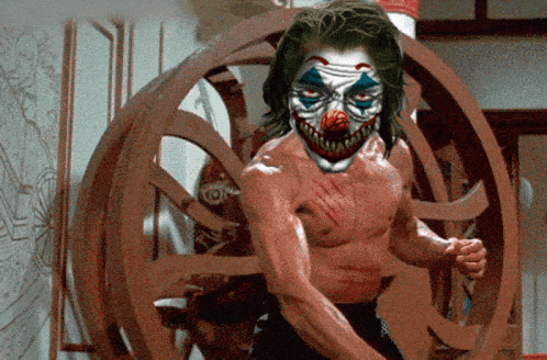 a man with a clown mask on his face is standing in front of a wooden wheel