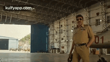 a man in a police uniform is standing in an airplane hangar .