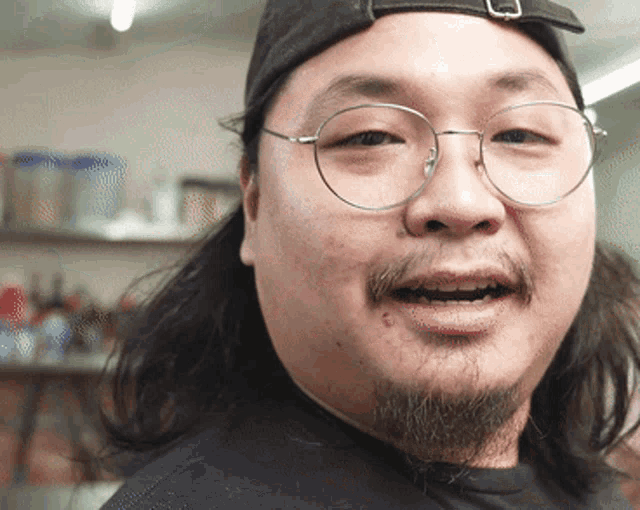 a close up of a man wearing glasses and a black hat