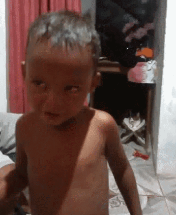 a shirtless little boy is standing in a living room .