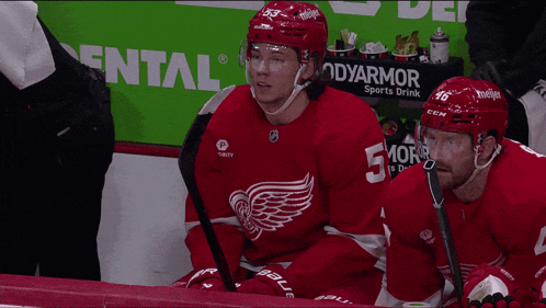 two hockey players are sitting in front of a dental ad