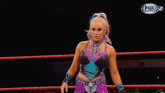 a woman is standing in a wrestling ring with a fox 2 logo in the background