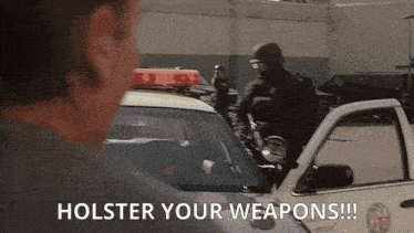 a man standing next to a police car with the words holster your weapons