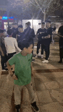a boy in a green nike shirt is standing in a crowd