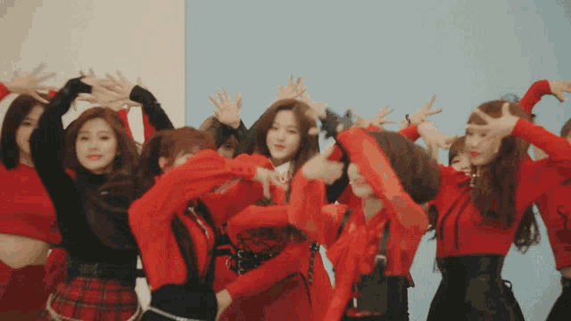 a group of young women in red dresses are dancing together