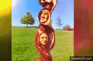 a picture of a tree trunk with faces carved into it is displayed on makeagif.com