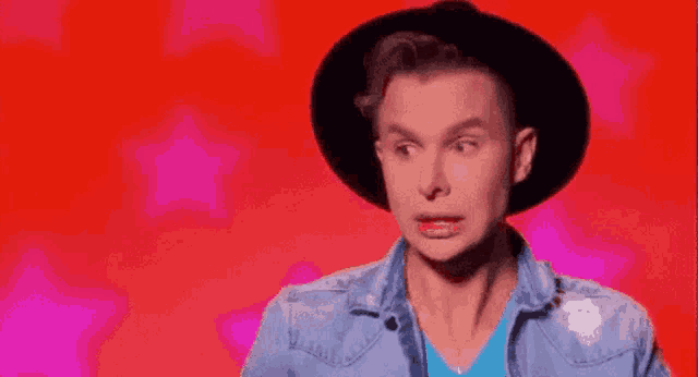 a man wearing a black hat and a blue denim jacket is making a funny face .