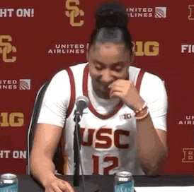 a woman in a usc jersey is sitting at a table with a microphone in front of her .