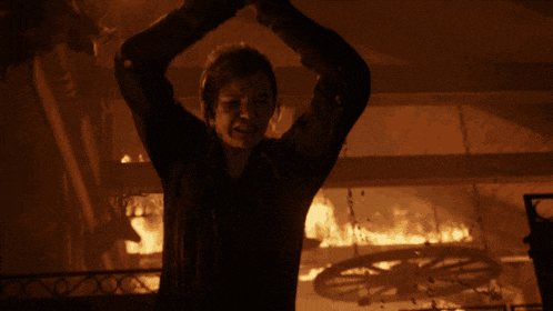 a woman holding a gun in front of a fire