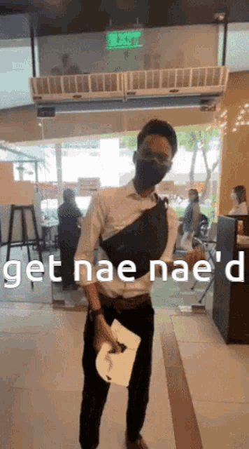 a man wearing a mask holds a piece of paper with the words get nae nae 'd written on it