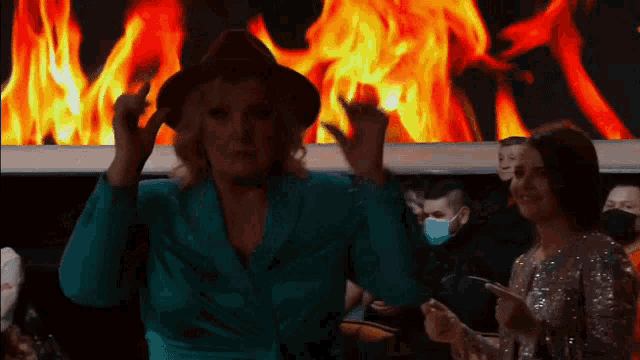 a woman wearing a hat is dancing in front of a fire