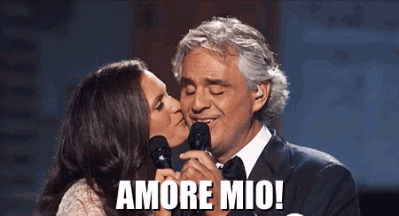 a woman kisses a man on the cheek while he sings into a microphone