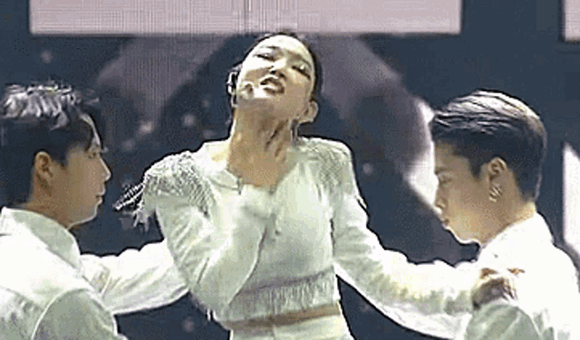a woman in a white dress is being held by two men .