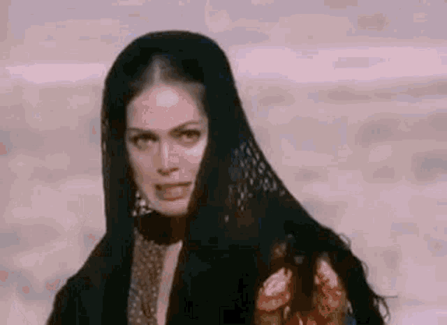 a woman is wearing a black scarf around her head and making a funny face .
