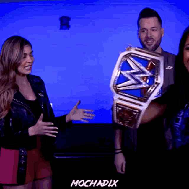 a man is holding a wwe championship belt while a woman stands behind him