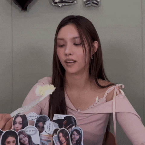a woman in a pink top is holding a piece of paper with a picture of a girl on it .