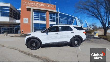 a white police car is parked in front of a calgary police service building