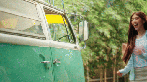a woman is standing in front of a green and white van